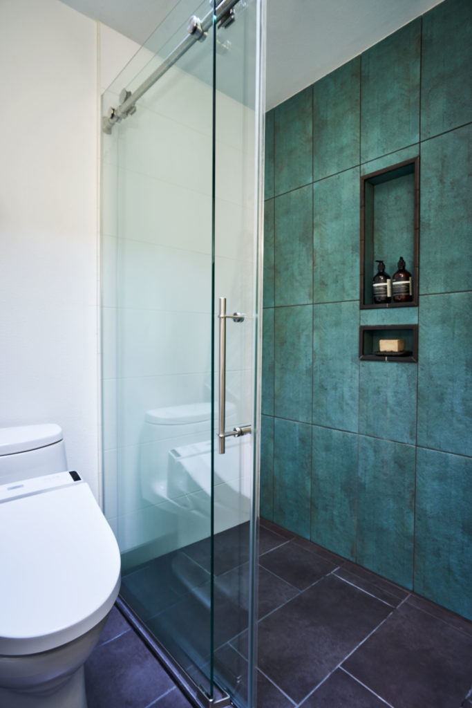 primary bath with curbless shower, sliding shower door, porcelain tile, custom niche