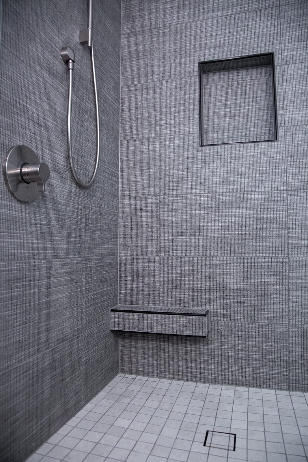 Textured tile shower surround with leg shaving shelf and tile in drain