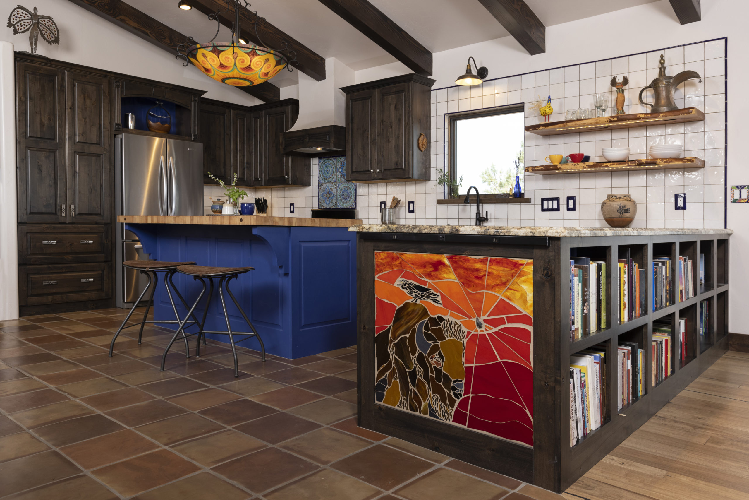 Kitchen with custom tile mosaic buffalo, painted island with butcher block, custom chandelier and built in bookshelves
