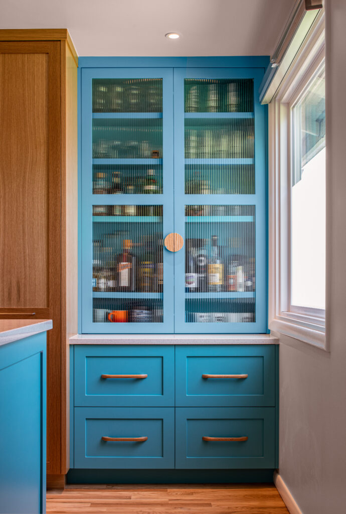 Blue bar cabinet with reeded glass, wood cabinet pulls, wood cabinetry