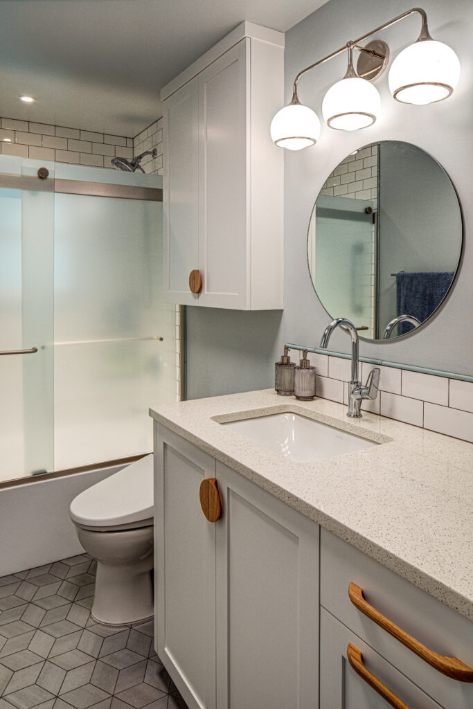 Bathroom with custom vanity, subway tile, toilet topper, sliding shower door, geometric mosaic floor tile