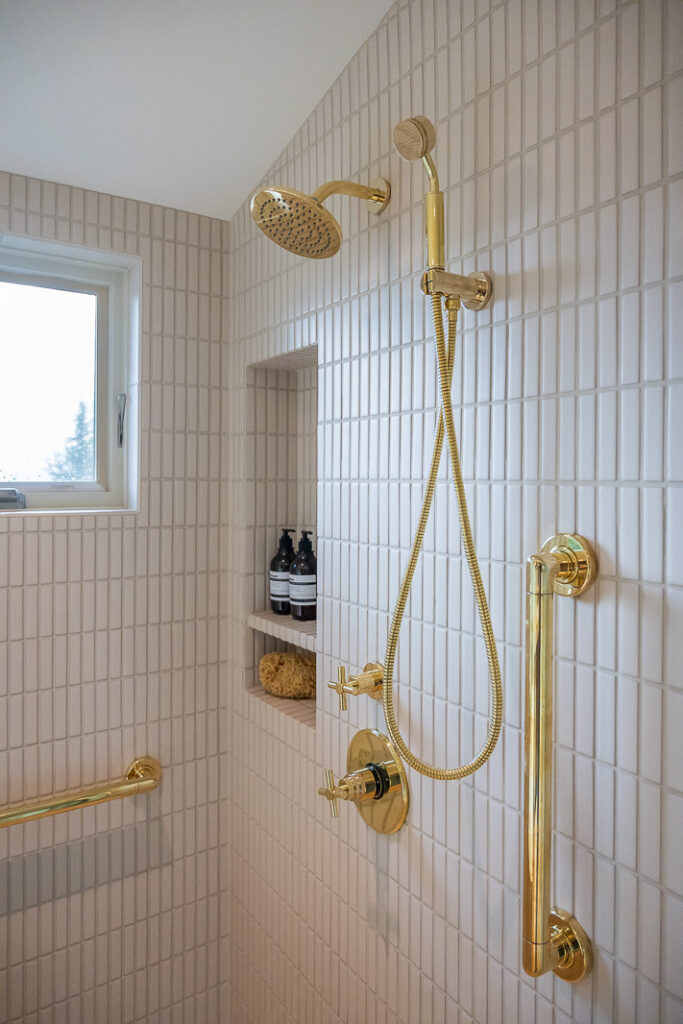 Unlaquered brass fixtures, stacked ivory tile in a shower